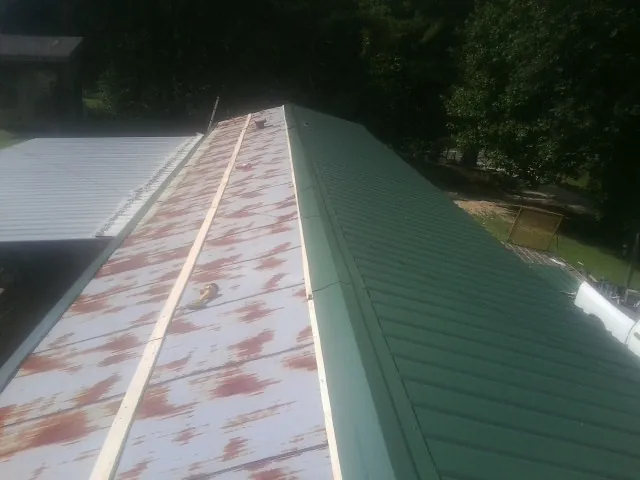 Old rusted panels beside newly installed green metal roofing — Wind Damage Roof Repair by Roofing Brothers in New Wilmington