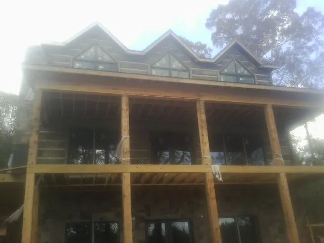 Dormers and porch framing on a large log home under construction — Roof Coating work by our crew in New Wilmington