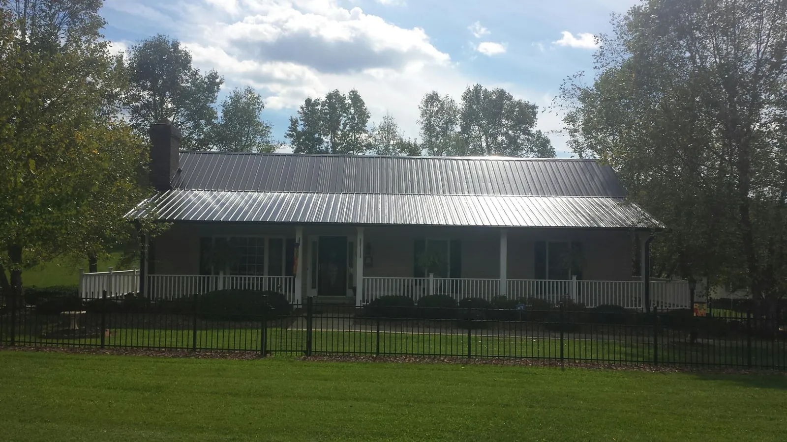 Gray metal roof on a brick ranch with a full width front porch — Gutter Guard Installation work by our crew in New Wilmington