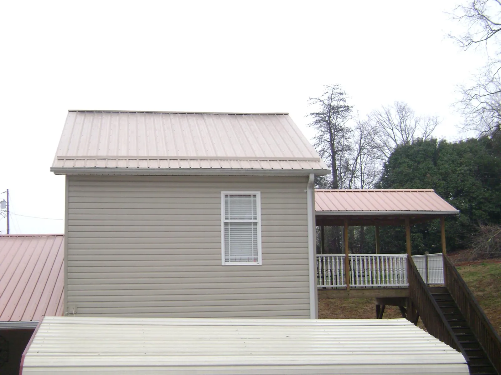 Tan metal roofs on a two story addition and attached porch, from a Roof Replacement job in New Wilmington