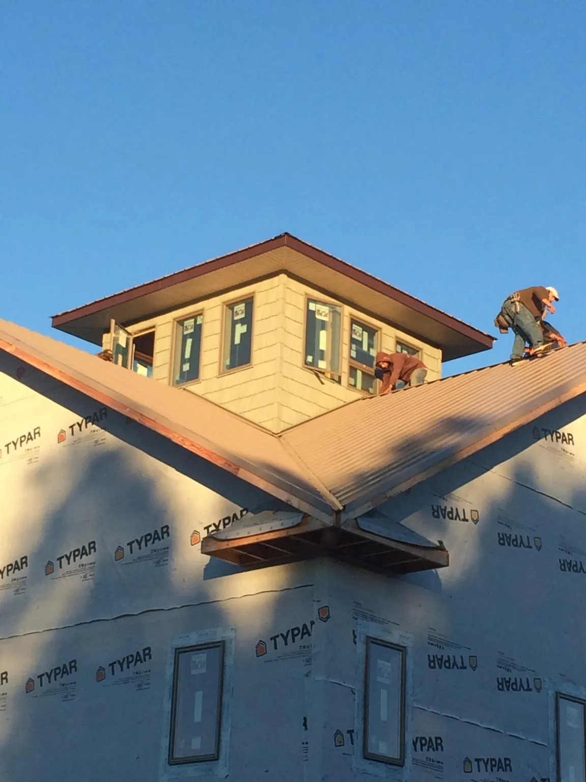 Roofers working around a rooftop cupola on a new metal roof at sunset — Roof Waterproofing in New Wilmington by Roofing Brothers